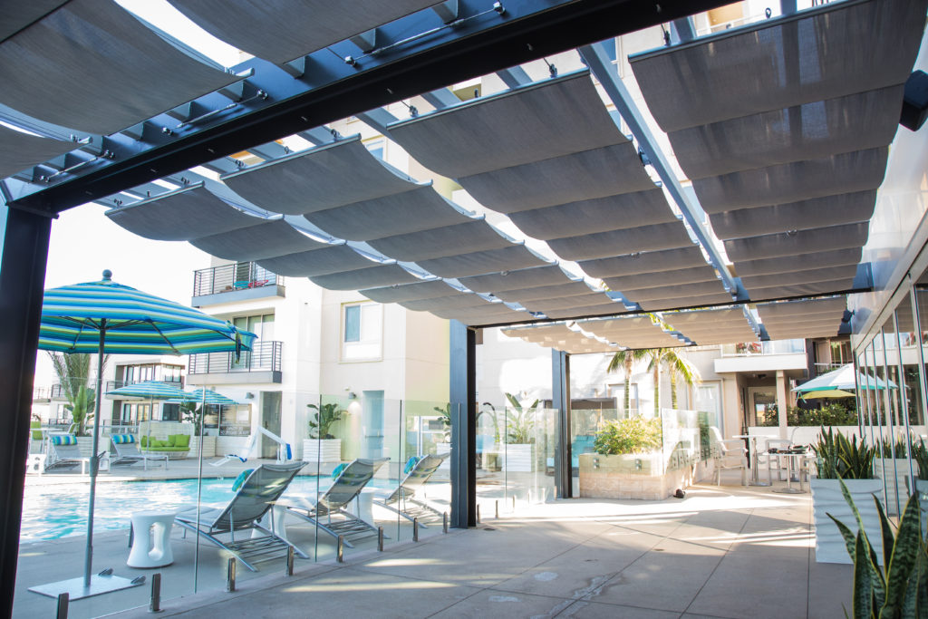 Retractable shade system covering patio by pool